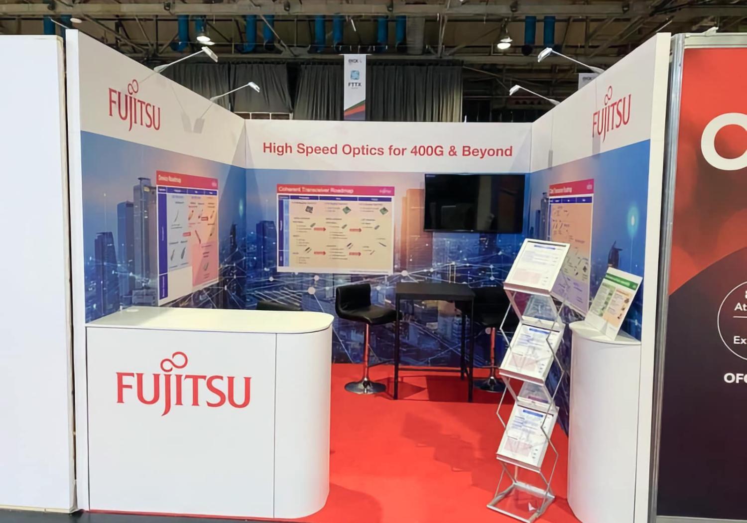 Fujitsu exhibition stand, 3 graphic walls with a tv screens, reception counter and a literature rack